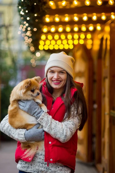 Cheerful young woman with a pet at the Christmas bazaar.