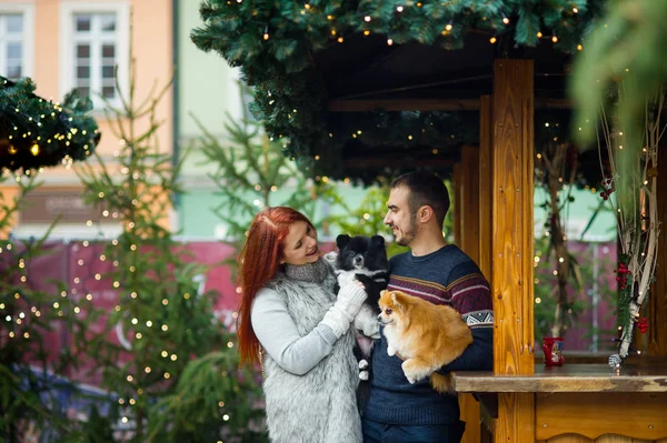 Christmas holidays. Young couple on the Christmas bazaar with pets.