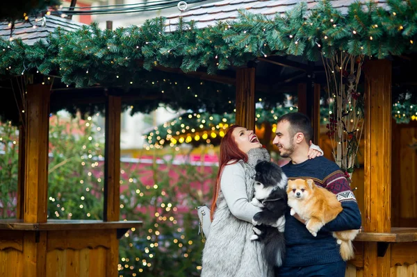 Christmas holidays. Young couple on the Christmas bazaar with pets. — Stock Photo, Image