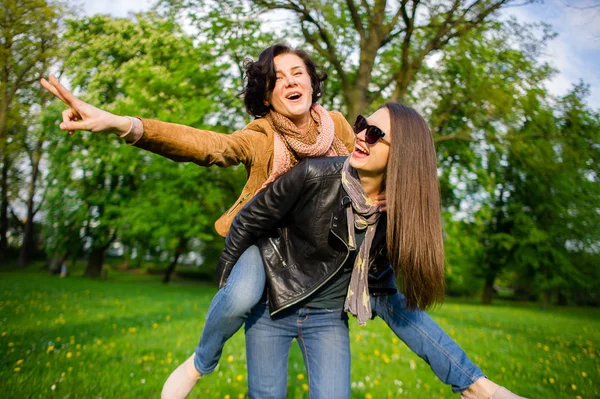 两位可爱的年轻女子在春天公园里高高兴兴地花时间 妇女有个好玩的心情 温暖阳光灿烂的日子 女朋友享受自然和通信 — 图库照片