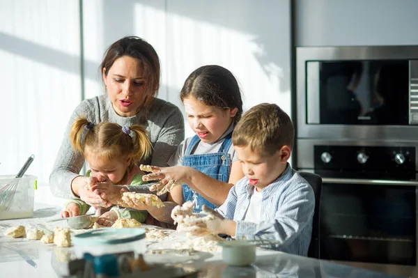 Matka i troje dzieci przygotować coś z ciasta. — Zdjęcie stockowe