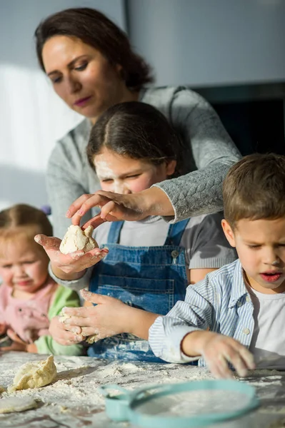 Mãe e três crianças preparam algo da massa . — Fotografia de Stock