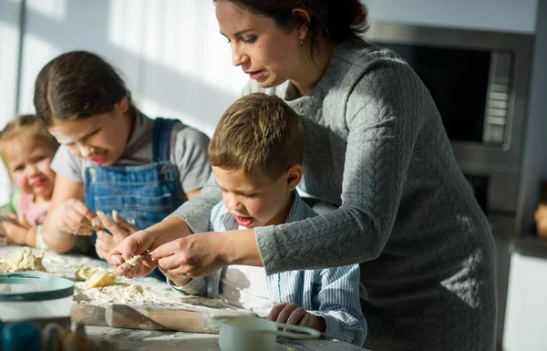 Mãe e três crianças preparam algo da massa . — Fotografia de Stock