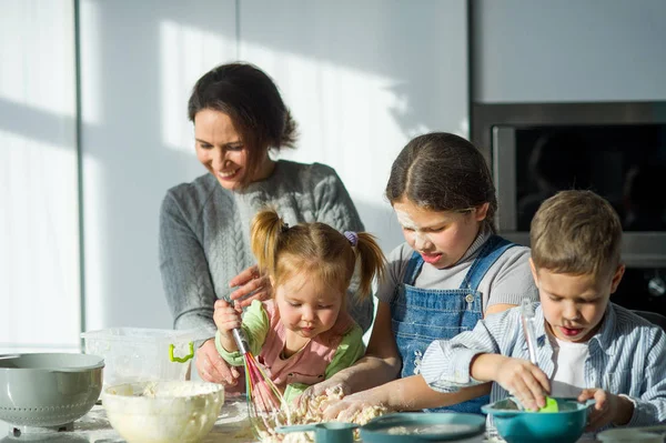 Mãe e três crianças preparam algo da massa . — Fotografia de Stock