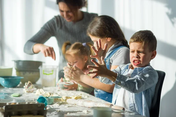 Mother and three children prepare something from the dough. — Stock Photo, Image