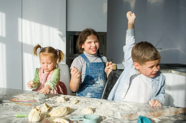 Three children prepare something from the dough. — Stock Photo, Image