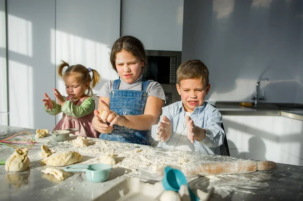 Trois enfants préparent quelque chose à partir de la pâte . — Photo