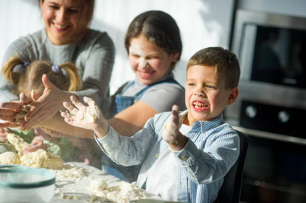 Mère et trois enfants préparent quelque chose à partir de la pâte . — Photo