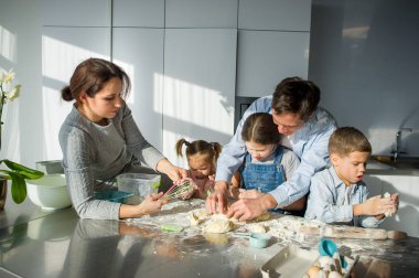 Geniş aile hamurdan bir şeyler hazırlar. Ebeveynler ve üç çocuk mutfak masasında. Mutlu ve kullanışlı eğlence.