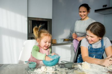 Annem iki küçük kızıma hamurdan yemek yapmayı öğretiyor. Zevkli çocuklar mutfak işleriyle meşguldür..