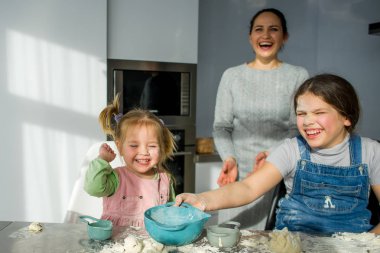 Annem iki küçük kızıma hamurdan yemek yapmayı öğretiyor. Zevkli çocuklar mutfak işleriyle meşguldür..