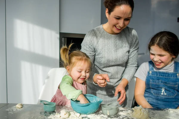 妈妈教两个小女儿用面团做饭 孩子们快乐地从事厨房的工作 — 图库照片