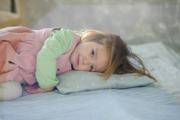 Little girl falls asleep on the bed. Baby is tired.