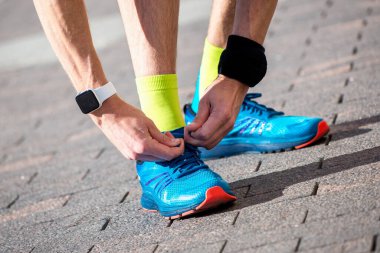 Bir sporcu maratondan önce ayakkabı bağcıklarını bağlar.