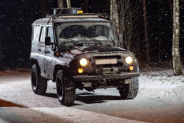 Bir cip karlı bir gece yolunda gidiyor.