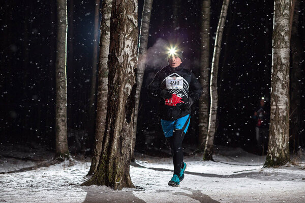 Athletes run along the track at night in the woods. Night race "Shatun trail" in Sosnovka Park 01.02.2020