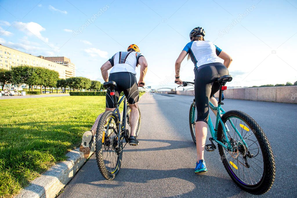 a man and a woman ride bicycles on the embankment