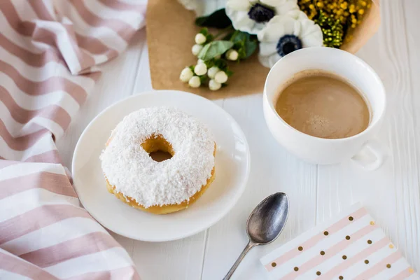 Café y una rosquilla con flores frescas — Foto de Stock