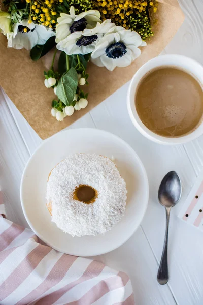 Καφέ και ένα ντόνατ με φρέσκα λουλούδια — Φωτογραφία Αρχείου