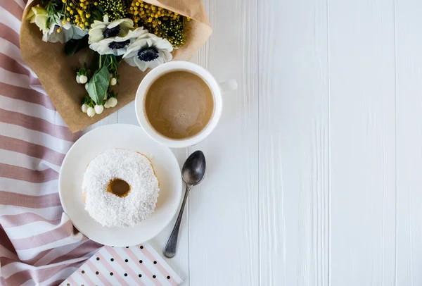 Koffie en een donut met verse bloemen — Stockfoto