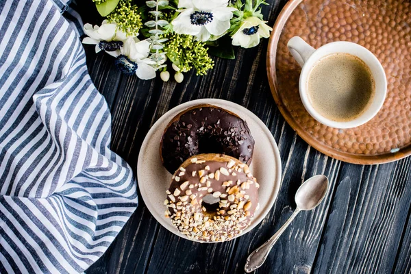 Kopje koffie en een chocolade donuts op zwart hout — Stockfoto