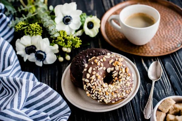 Fincan kahve ve bir çikolatalı donuts siyah ahşap üzerine — Stok fotoğraf