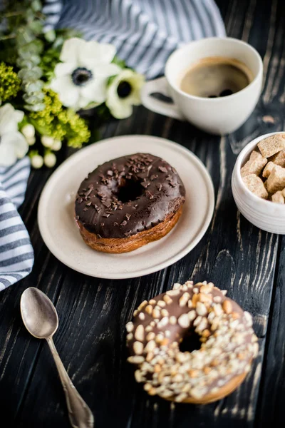 Kopje koffie en een chocolade donuts op zwart hout — Stockfoto