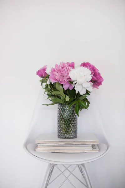 Bloemen decor, verse pioenrozen op ontwerper stoel in witte kamer int — Stockfoto