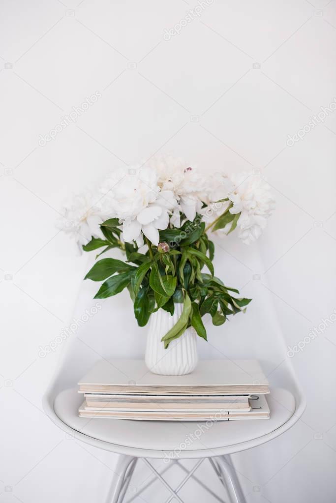 flowers decor, fresh peonies on designer chair in white room int