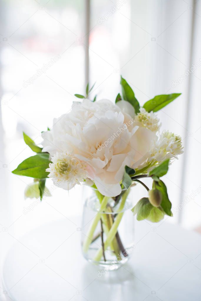 white peony flowers on coffee table in white room interior, brig