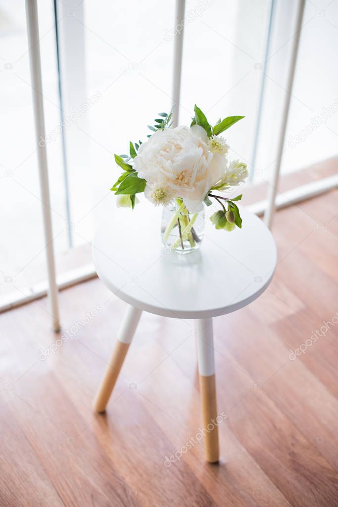 white peony flowers on coffee table in white room interior, brig
