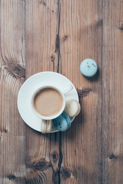 Šálek kávy a modré makronky na dřevěný stůl pozadí — Stock fotografie