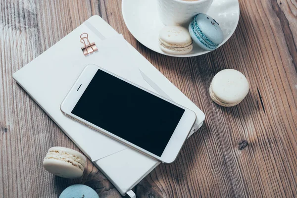 Tasse Kaffee, blaue Makronen und Smartphone auf Holztisch — Stockfoto