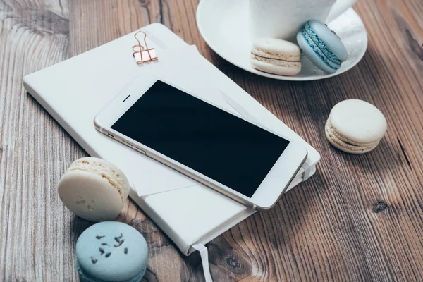 Kopje koffie, blauwe bitterkoekjes en smartphone op houten tafel bac — Stockfoto