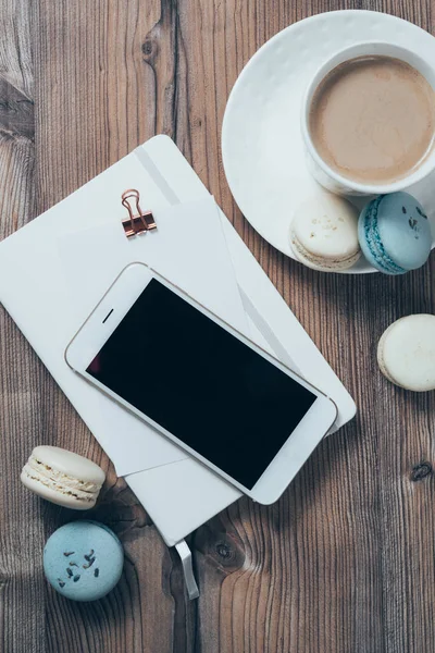Kopje koffie, blauwe bitterkoekjes en smartphone op houten tafel bac — Stockfoto