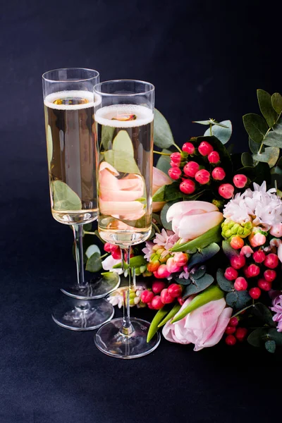 Two glasses of champagne and bouquet of pink flowers — Stock Photo, Image