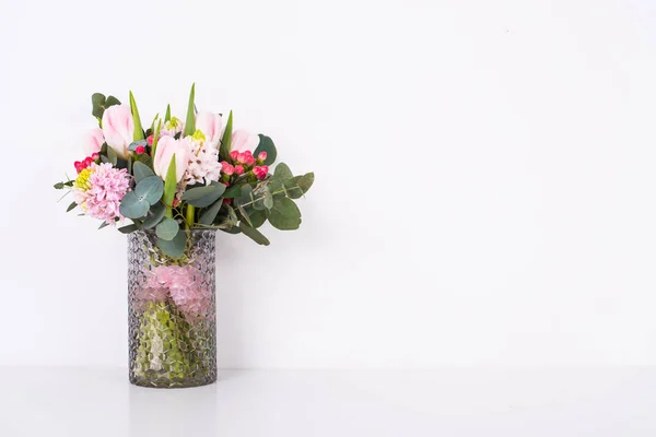 Boquet de flores rosadas en jarrón por pared blanca —  Fotos de Stock