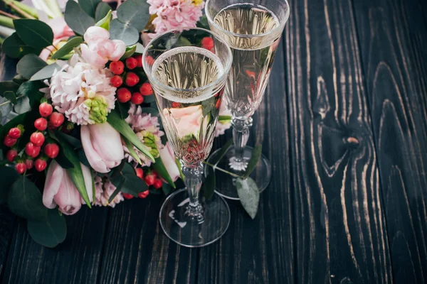 Deux verres de champagne et bouquet de fleurs roses sur woo foncé — Photo