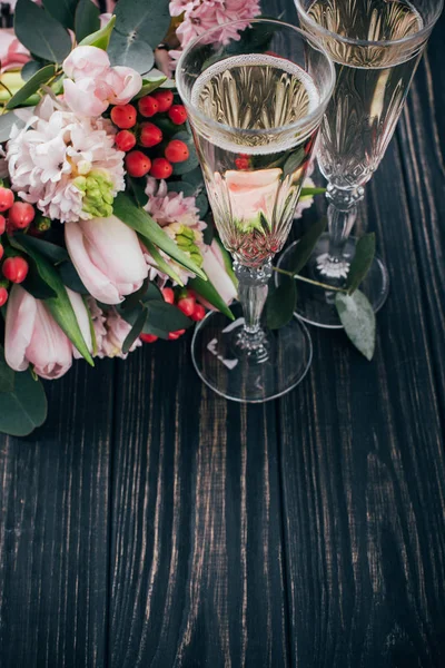 Twee glazen van champagne en boeket van roze bloemen op donker woo — Stockfoto