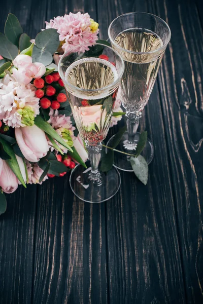 Dwie szklanki szampana i bukiet kwiatów róż na ciemny woo — Zdjęcie stockowe