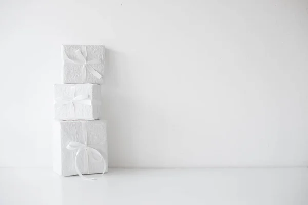 Drei weiße Geschenkboxen mit Schleifen auf dem Tisch — Stockfoto