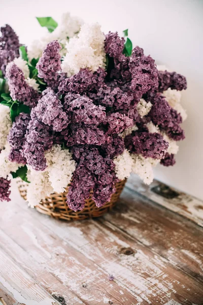 Boeket van wit en paars lila bloemen in rieten mand op ta — Stockfoto