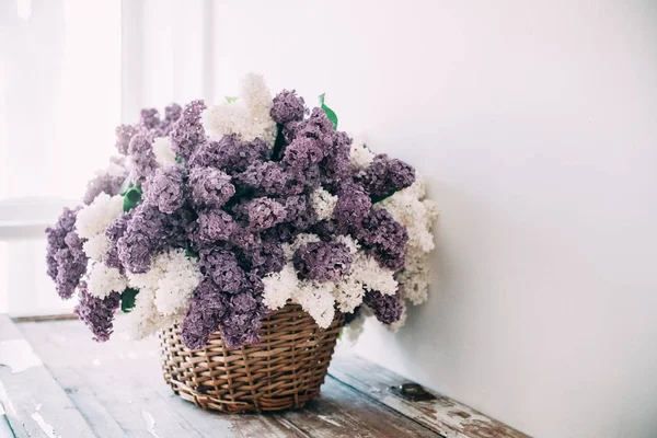 Kytice bílá a fialová lila květy v proutěném koši na ta — Stock fotografie