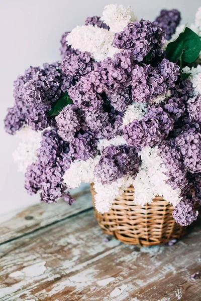 Boeket van wit en paars lila bloemen in rieten mand op ta — Stockfoto