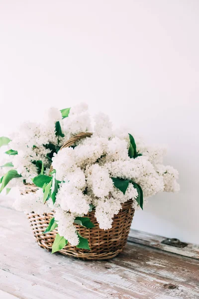 Boeket van verse witte lila bloemen in rieten mand op houten — Stockfoto