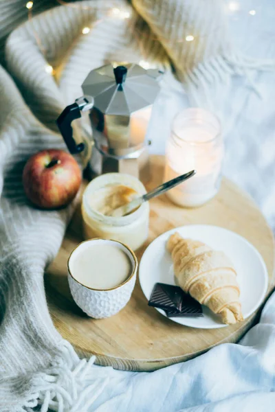 Útulná zimní víkendová snídaně, káva a croissant na dřevěném podnosu — Stock fotografie