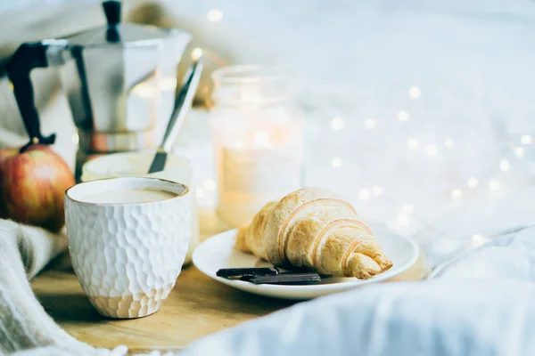 Útulná zimní víkendová snídaně, káva a croissant na dřevěném podnosu — Stock fotografie