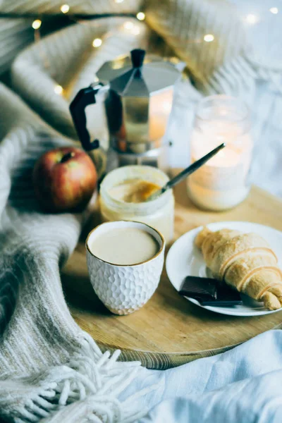 Útulná zimní víkendová snídaně, káva a croissant na dřevěném podnosu — Stock fotografie