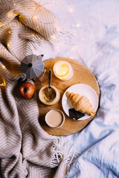 Útulná zimní víkendová snídaně, káva a croissant na dřevěném podnosu — Stock fotografie