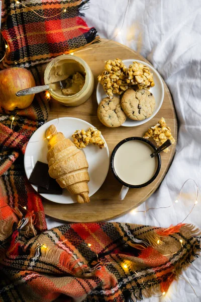 Petit déjeuner maison de campagne simple au lit, café avec lait et pâtisserie maison sur couverture à carreaux — Photo